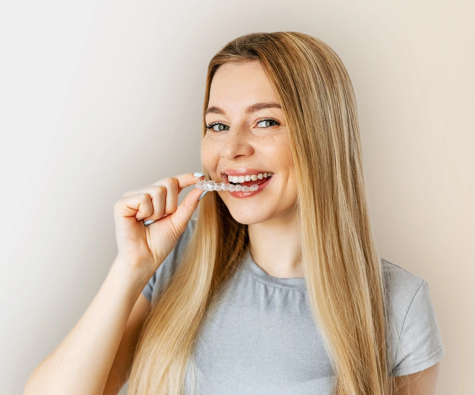 Young woman smiling while brushing teeth against white background, dental care concept