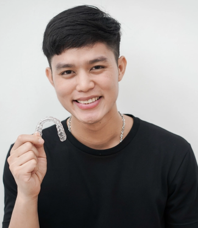 Young man smiling at camera wearing black shirt, professional headshot against white background.