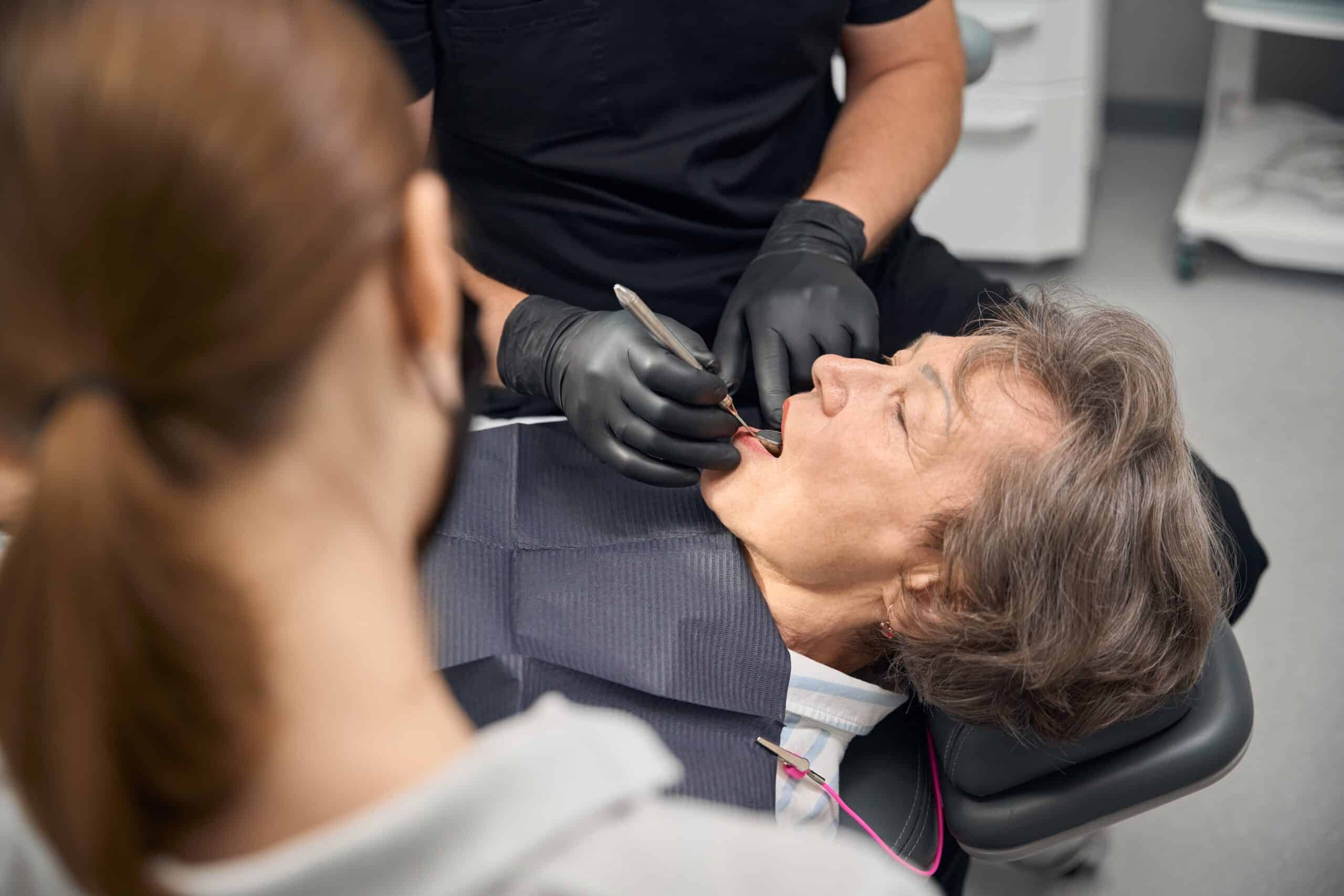 Dentist examining patient's teeth during dental implant consultation in Phoenix.