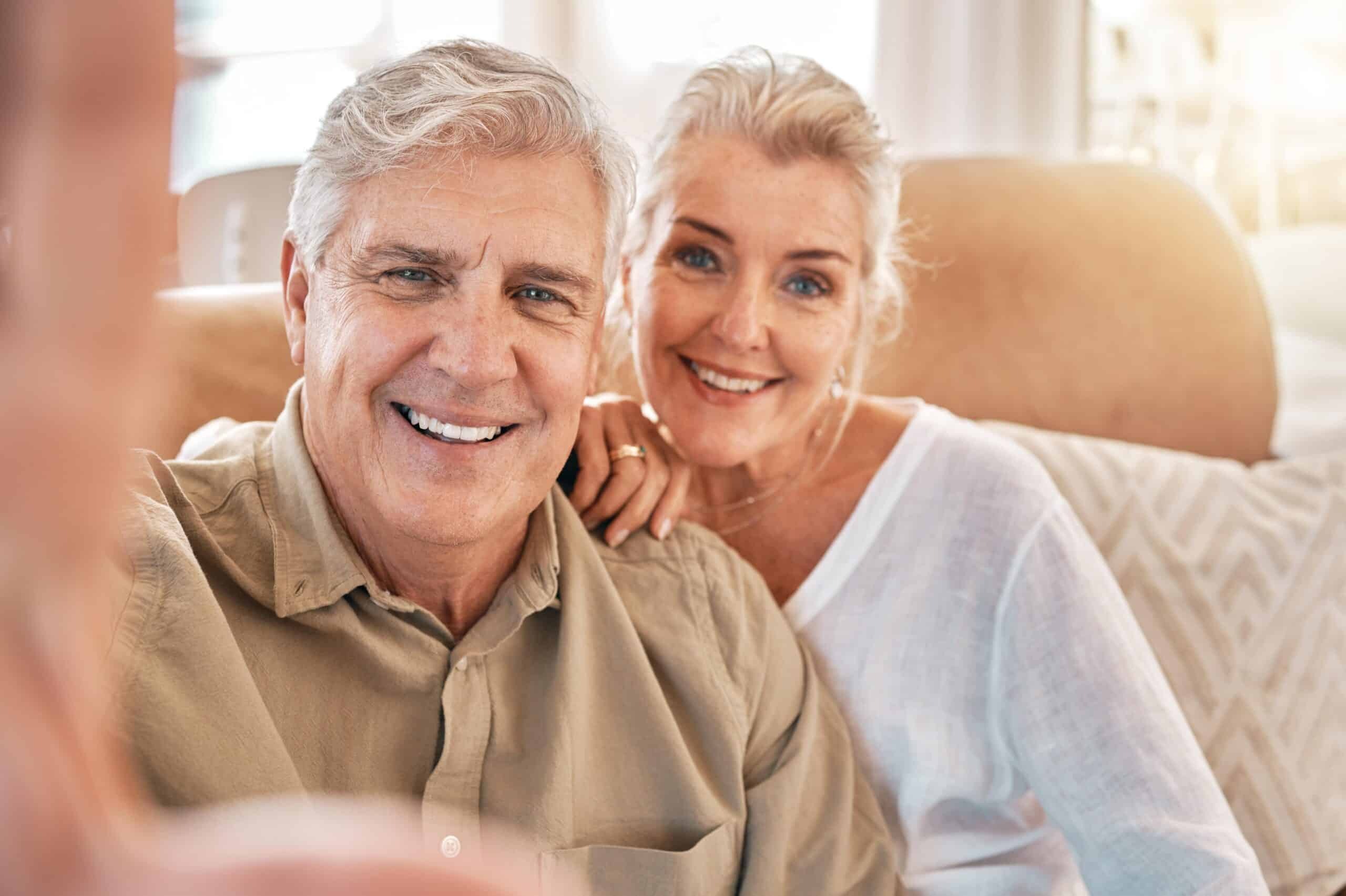 Happy senior couple smiling together in dental office setting.