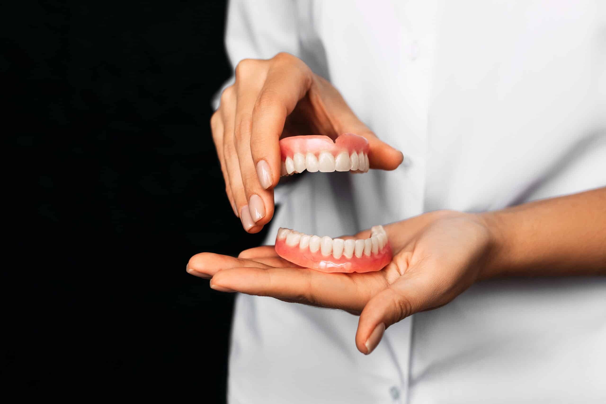 Dentist showing upper and lower dentures to patient during consultation.